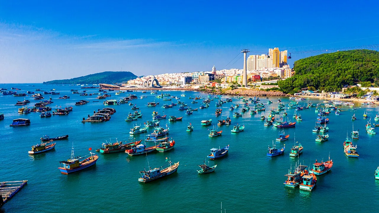 Aerial view of An Thới fishing harbour with colourful wooden boats, Sunset Town and the Hon Thom cable car tower visible in the background, Phú Quốc Island, Vietnam.